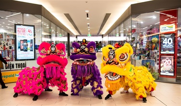 3 lion dancers in pink, purple and yellow costumes in Dutton Plaza hallway