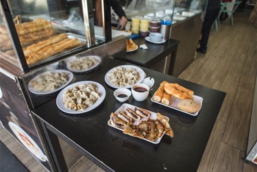 Plates with dumplings, sauce and other food on a dining table at Li's Wok in Dutton Plaza