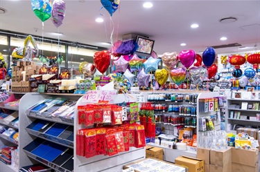 Inside Mitchum Newsagency at Dutton Plaza showing range of products including stationery, stickers, paints, Asian lanterns and chrome party balloons