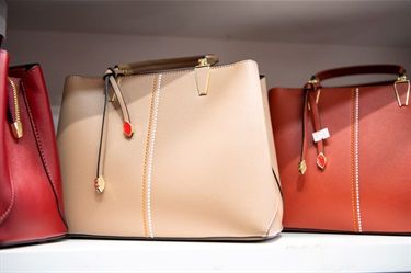 Beige and red handbags on shelf at Niko Fashion in Dutton Plaza