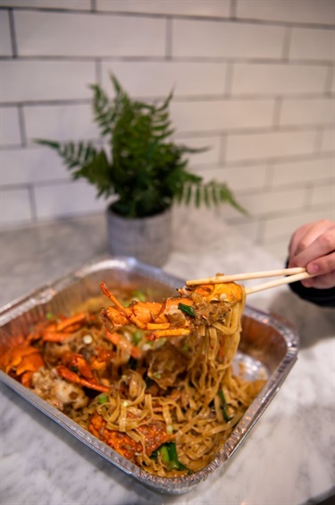 Chopsticks holding up a piece of crab and noodle meal at Viet Hoa Oyster Bar in Dutton Plaza