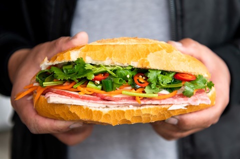 Close up of hands holding a bánh mì baguette at Daily Delicious Bakery in Dutton Plaza